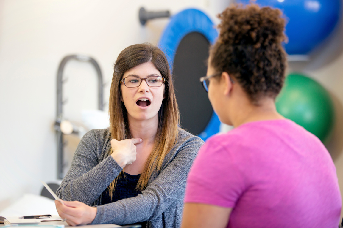 Young female speech therapist helping a young female in therapy