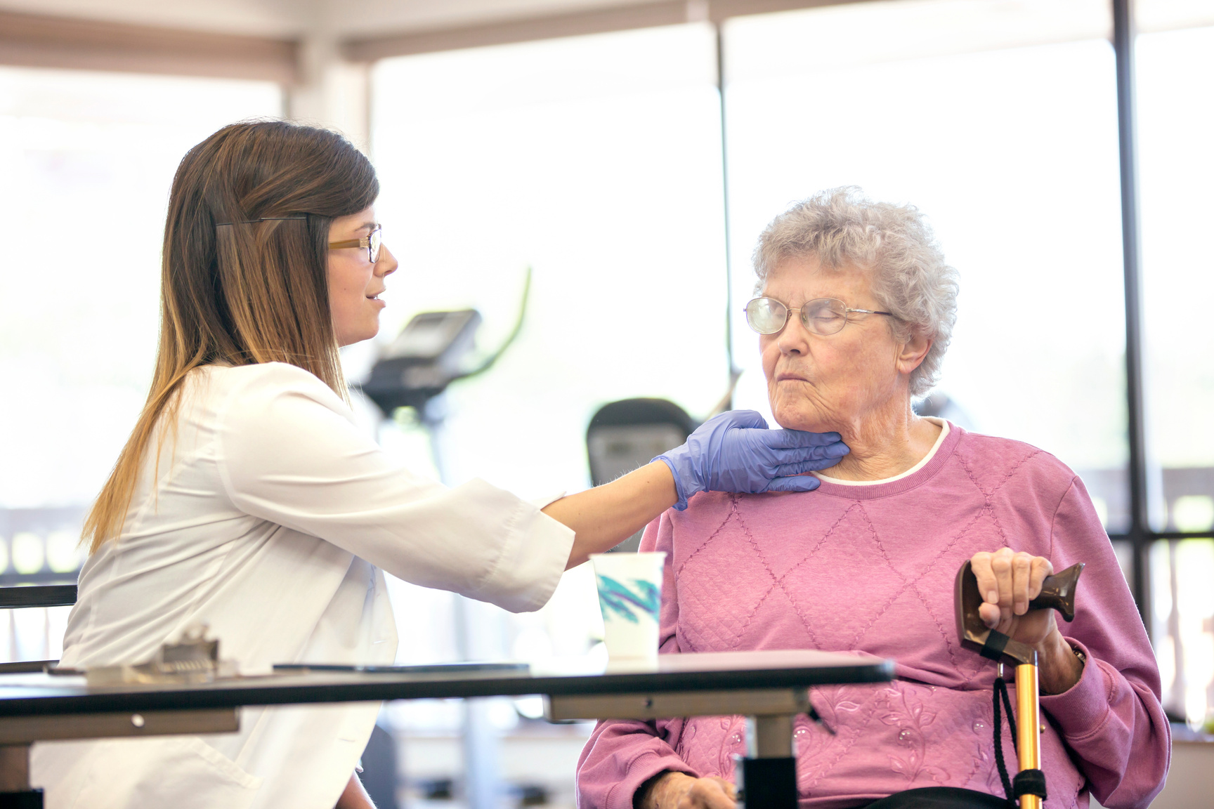 Female therapist testing elderly womans ability to swallow